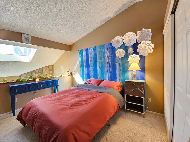 Large bedroom that overlooks the fireplace/living room with a beautiful skylight, and a large closet with extra storage above.