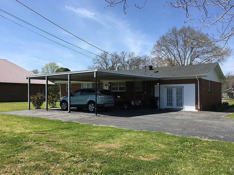 From Hillcrest Drive. Back entry into bonus room with double doors. Generous sized car port covers back door entry into kitchen/dining area.