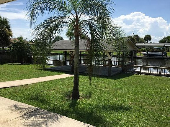 View of back yard with large boathouse and fenced water access.