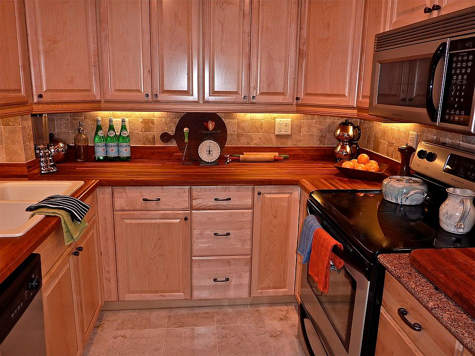 Kitchen features stainless steel appliances, butcher block and granite countertops, marble floors