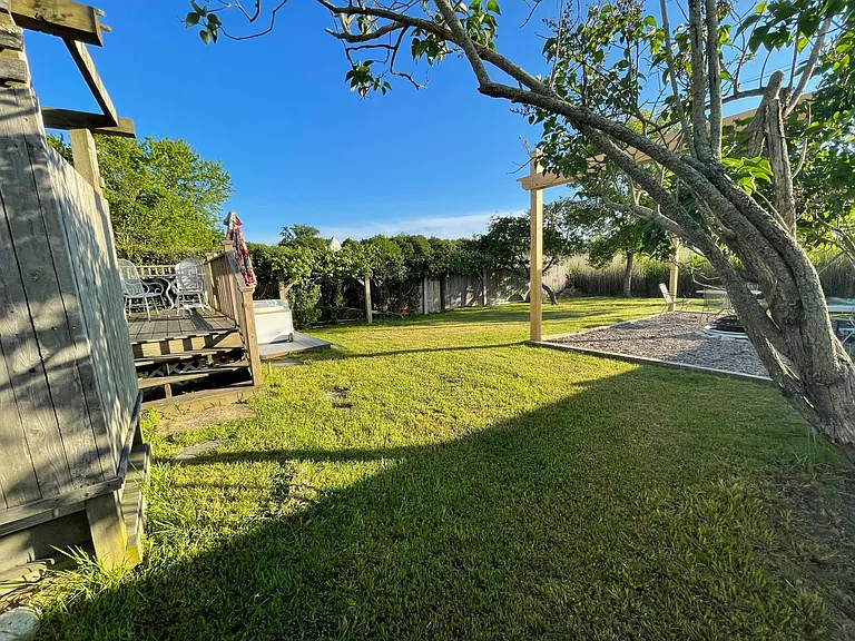 A view of the yard showing the rustic outdoor heated shower, air jet tub, and fire pit lounge.