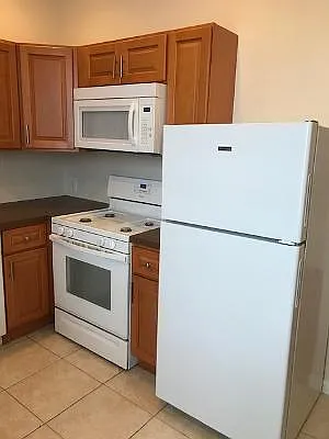 Kitchen with tile floor with dishwasher, garbage disposal, microwave.