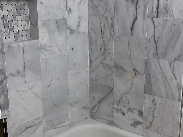 Marbled full bathroom with tub.