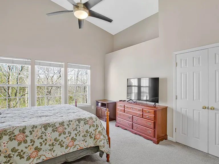 Spacious, light-filled, and lined with oversized picture windows, the primary bedroom feels like a quiet retreat above the trees.