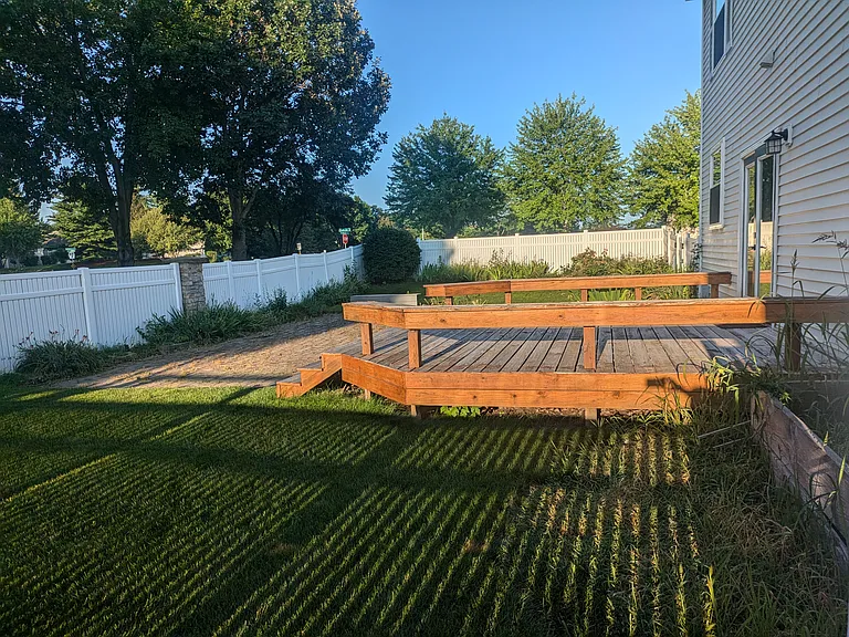 Fully fenced in backyard with wood deck and large brick patio