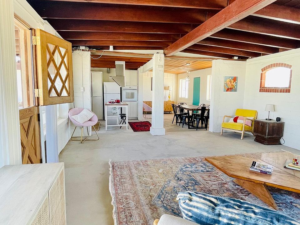 Living room looking into dining area and kitchen. Farmhouse door opening up to back patio and outdoor space.