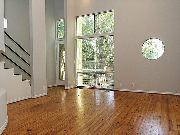 The living area has large windows , , two story ceilings and pine floors. You can see the shaded yar