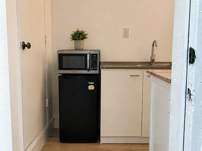 Welcome in _ Just inside the private entrance, you'll find a functional kitchenette with a mini fridge, sink, cabinet storage, and additional counter space.