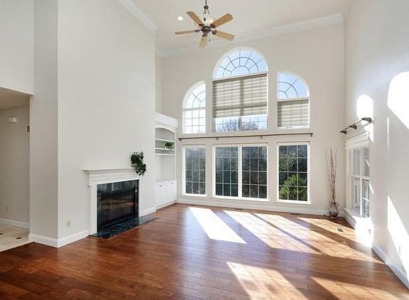 Grand Great Room with fireplace, wood floors and enormous windows that fill the home with warm, natural light.