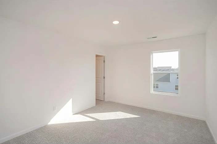 Spacious secondary bedroom featuring ample natural light and a dedicated walk-in closet for organized storage.