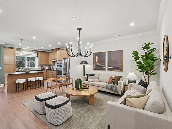 A modern and cozy open-concept living room and kitchen area with wooden floors, neutral-toned furnit