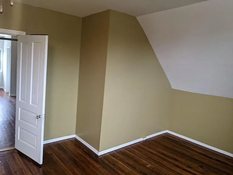 Large third floor bedroom with newly refinished hardwood floors.