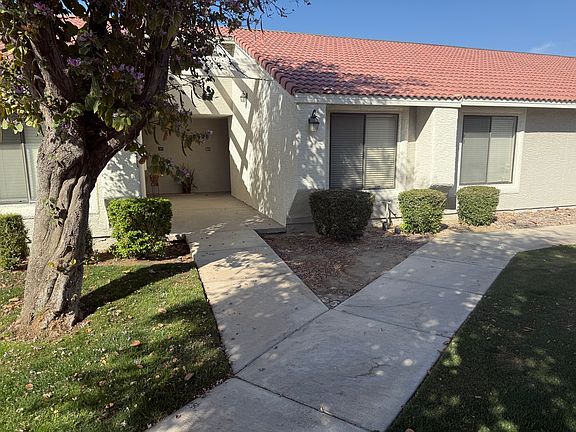 Exter elevation of unit from entry shaded by large tree.