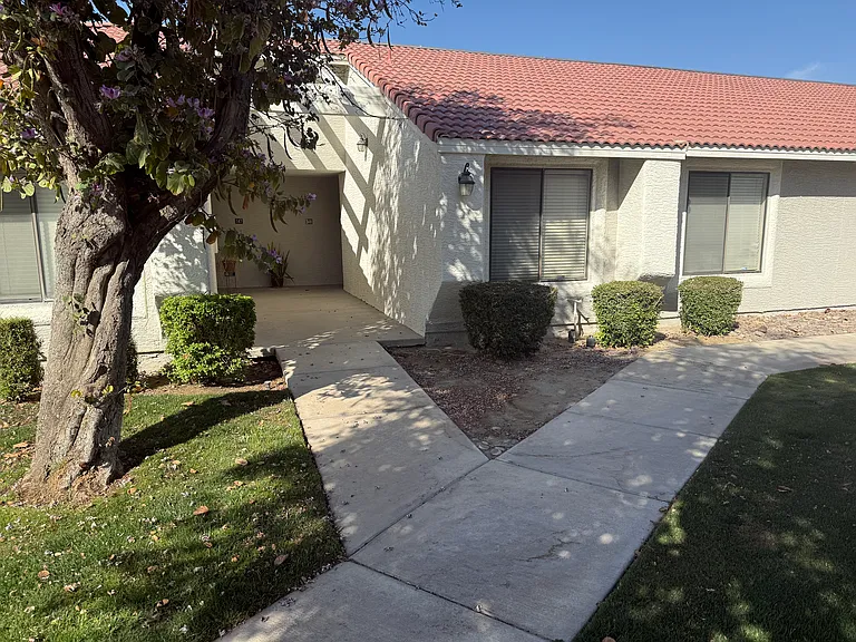 Exter elevation of unit from entry shaded by large tree.