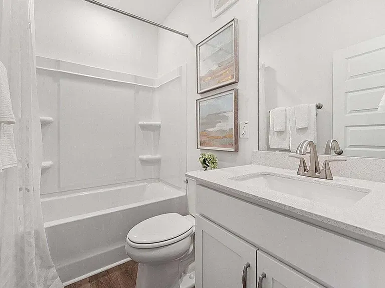 Well-appointed shared full bath serving the additional bedrooms features a tub/shower combination, ample vanity storage, and adjacent linen closet and laundry area with a brand-new front-load washer and dryer.