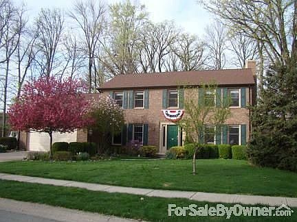 Colonial-style, two-story house with professional landscaping.