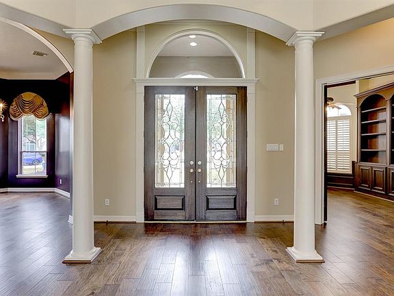 You will enter the home through the double leaded glass doors with overhead transom window to the foyer with decorative pillars and hard wood floors.