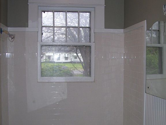 Bathroom with fully tiled shower and pedestal sink.