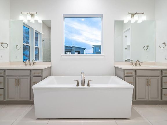 Primary bath with dual vanities, a freestanding tub, and walk-in shower