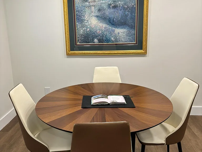 Dedicated dining nook with a round table for four, comfortable seating, and wall artideal for meals or study time.