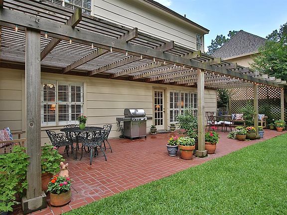 LARGE ENTERTAINING SPACE: The brick-paved patio with pergola offers lots of space for enjoying family meals outdoors and for entertaining friends. The owners arrangement shows that there is room for seating and dining tables anchoring both ends.