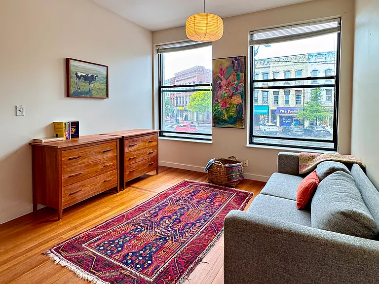 Living room with clean-line couch and double cherry wood dressers.