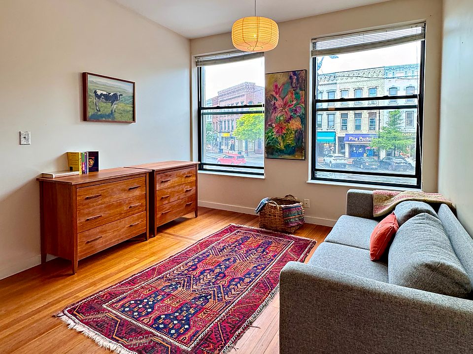 Living room with clean-line couch and double cherry wood dressers.