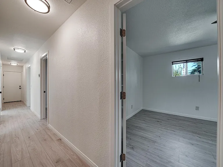 View down hallway and into master bedroom. Fresh coat of pain and new light fixtures throughout along with new vinyl flooring!