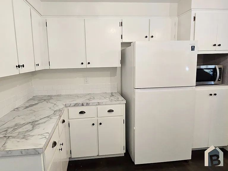 Kitchen with brand new countertops, stove, sink, faucet, microwave, & backsplash.