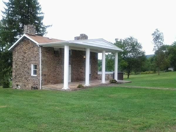 Front of the house with spacious yard and stone patio/porch 