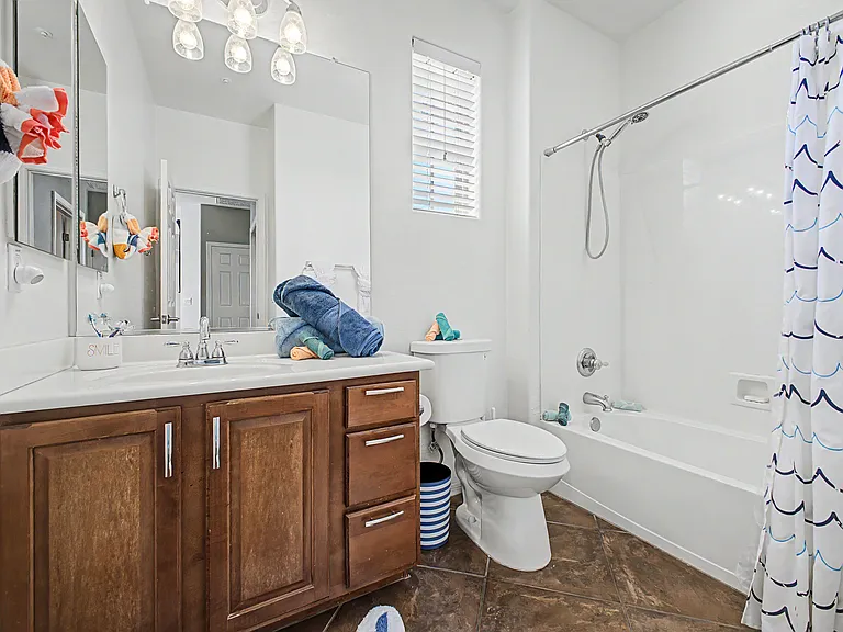 This upstairs bathroom serves the two secondary bedrooms and features a full bathtub with shower, along with ample drawer space for storing personal belongings.