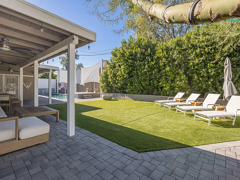Rare in 85014: A spacious, fully private backyard oasis with mature ficus trees, covered furnished patio, sun loungers, and sparkling pool