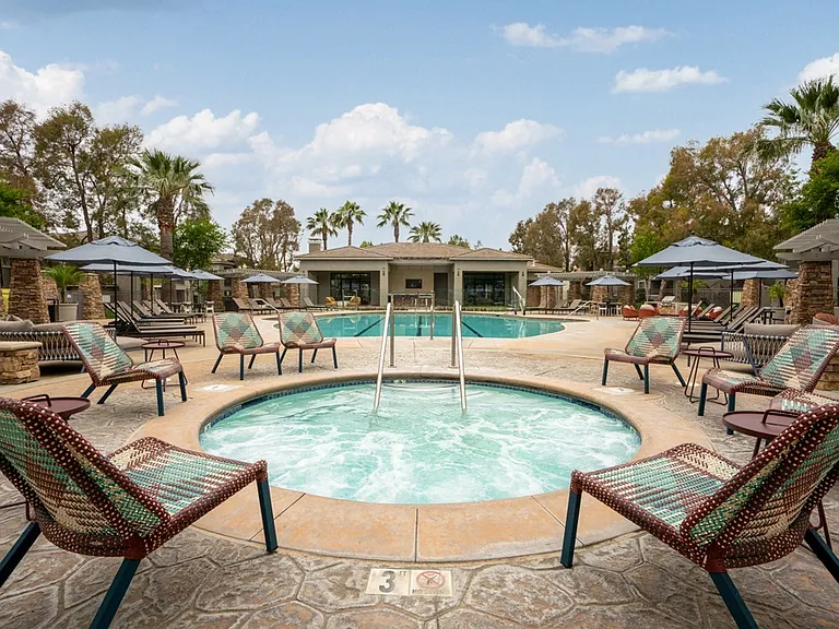 Outdoor Hot Tub Surrounded by Woven Chairs and Resort-Style Pool Deck