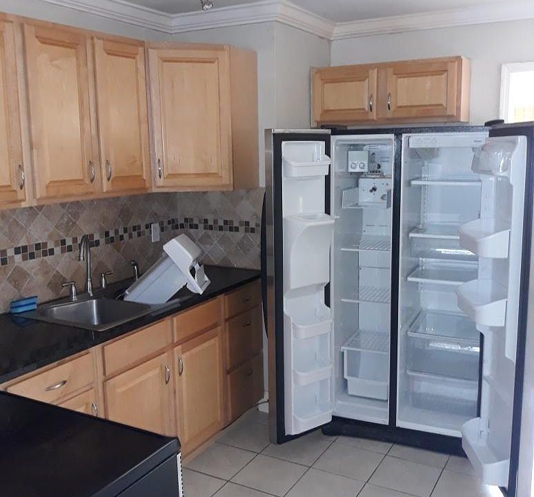 Kitchen with glass top electric stove and side by side refrigerator.