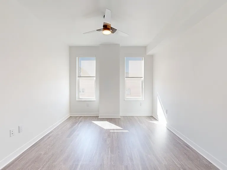 Spacious apartment bedroom with wood-style flooring.