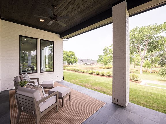 A cozy outdoor patio with comfortable seating overlooking a lush, green lawn and trees in the backgr