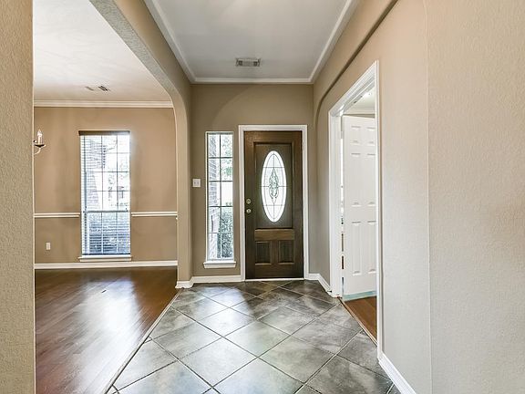 View of Entry, and 18" diagonally laid ceramic tile, leaded glass door, Dining Room with Hardwoods and chair and crown  mouldings. Living Room to the right also has Hardwood floors.