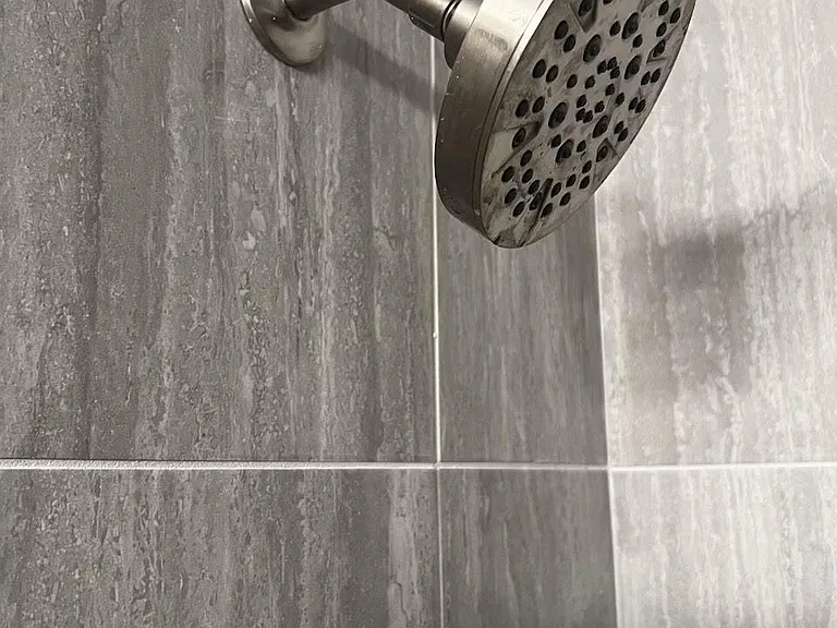 Detail of the gray large-format bathroom tile in an all-new bathroom with a large shower.