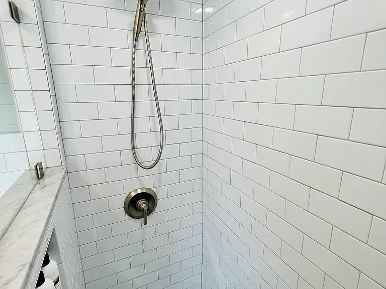 Private bath with floating sink, storage and shower.