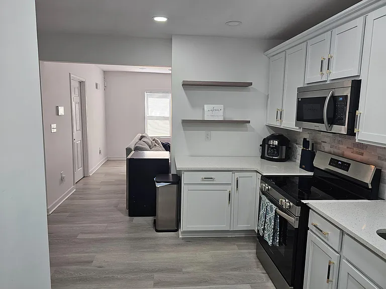 Updated kitchen with shaker cabinetry, quartz-look counters, and stainless range and microwave, opening to the living area.