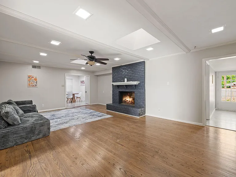 Spacious living area with hardwood floors, recessed lighting, ceiling fan, and a brick fireplace, plus easy flow to dining.