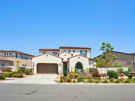 Front Exterior of home including a bocce ball court to the right in front of fence