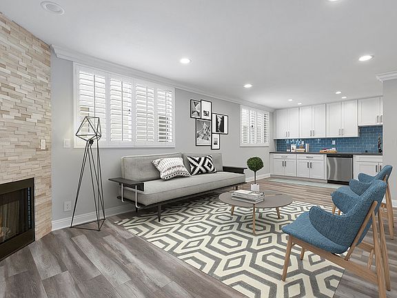 Brightly lit living room with stone walled fireplace.