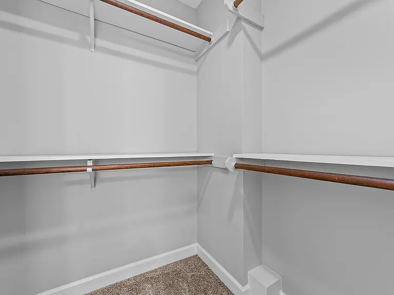 Walk-in closet with built-in shelving and wood hanging rods for organized storage.