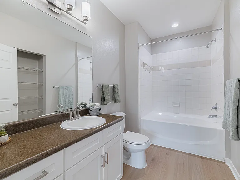 Bathroom with white cabinetry, hardwood floors, and storage