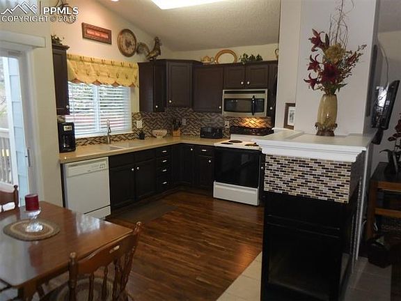 Lovely kitchen has granite countertops and laminate wood floor.