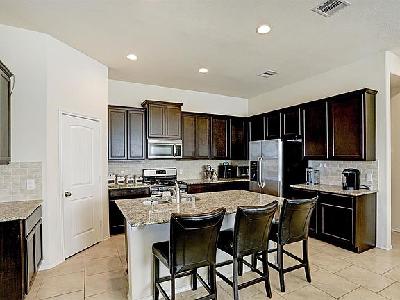 The kitchen boasts granite counter tops, stainless steel appliances, and a large breakfast bar.
