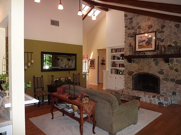 Living room with stone fireplace, wood floors, high ceilings and french doors.
