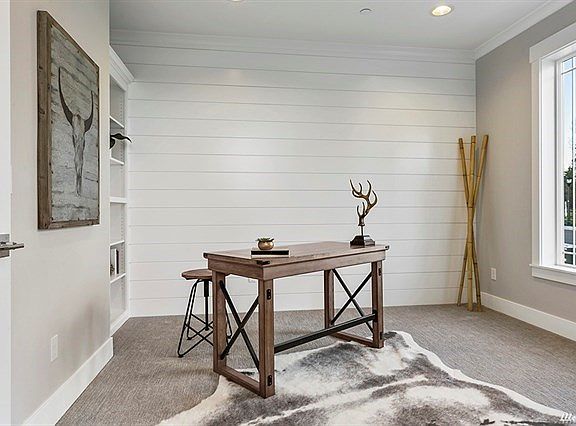 Den features built in bookcase and shiplap on the wall.