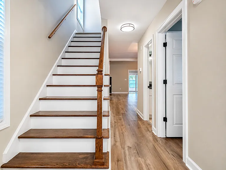 Front entrance with staircase leading to second floor. Downstairs bedroom & bathroom on right, with kitchen and living room beyond.